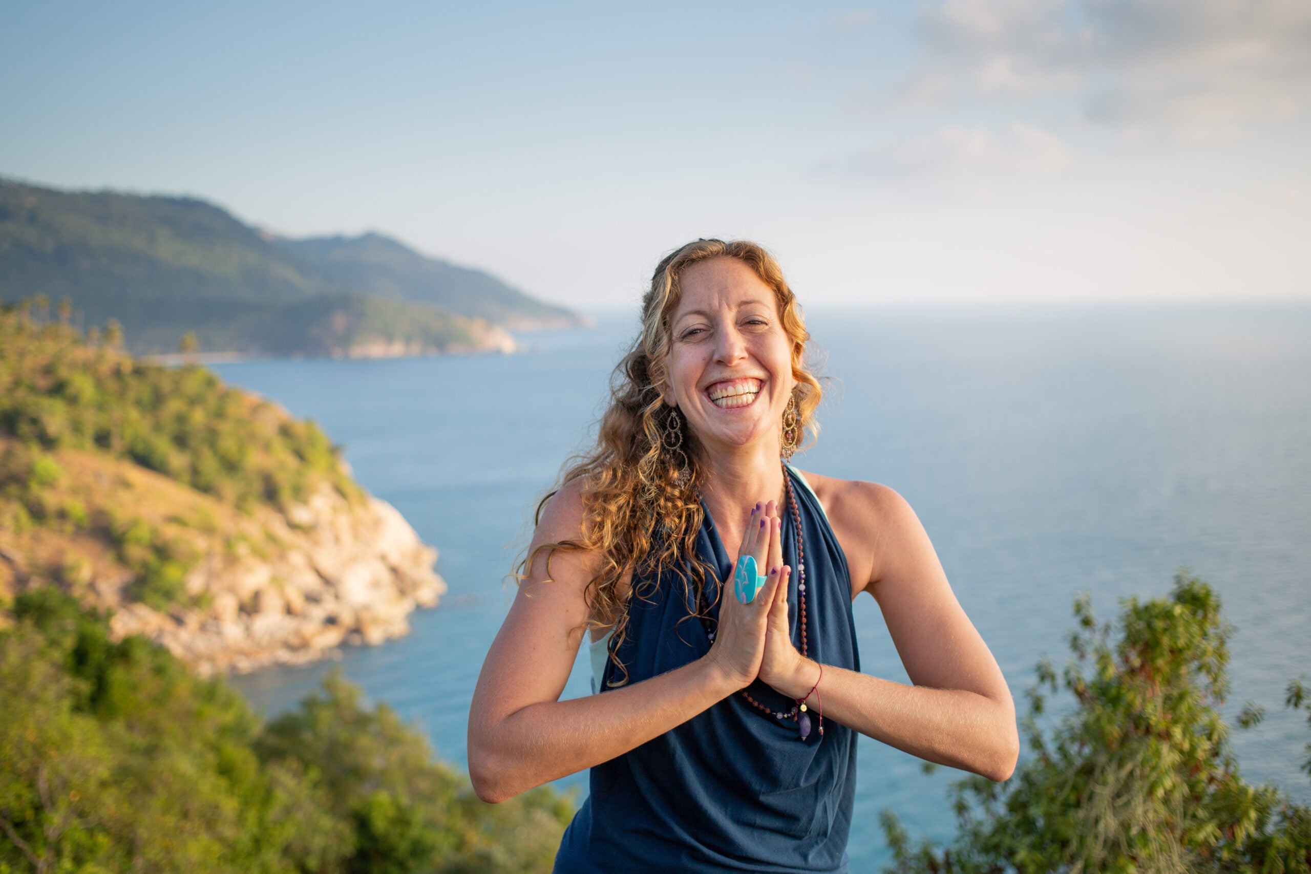 Francie smiling with her hands at her heart on a lookout above the sea