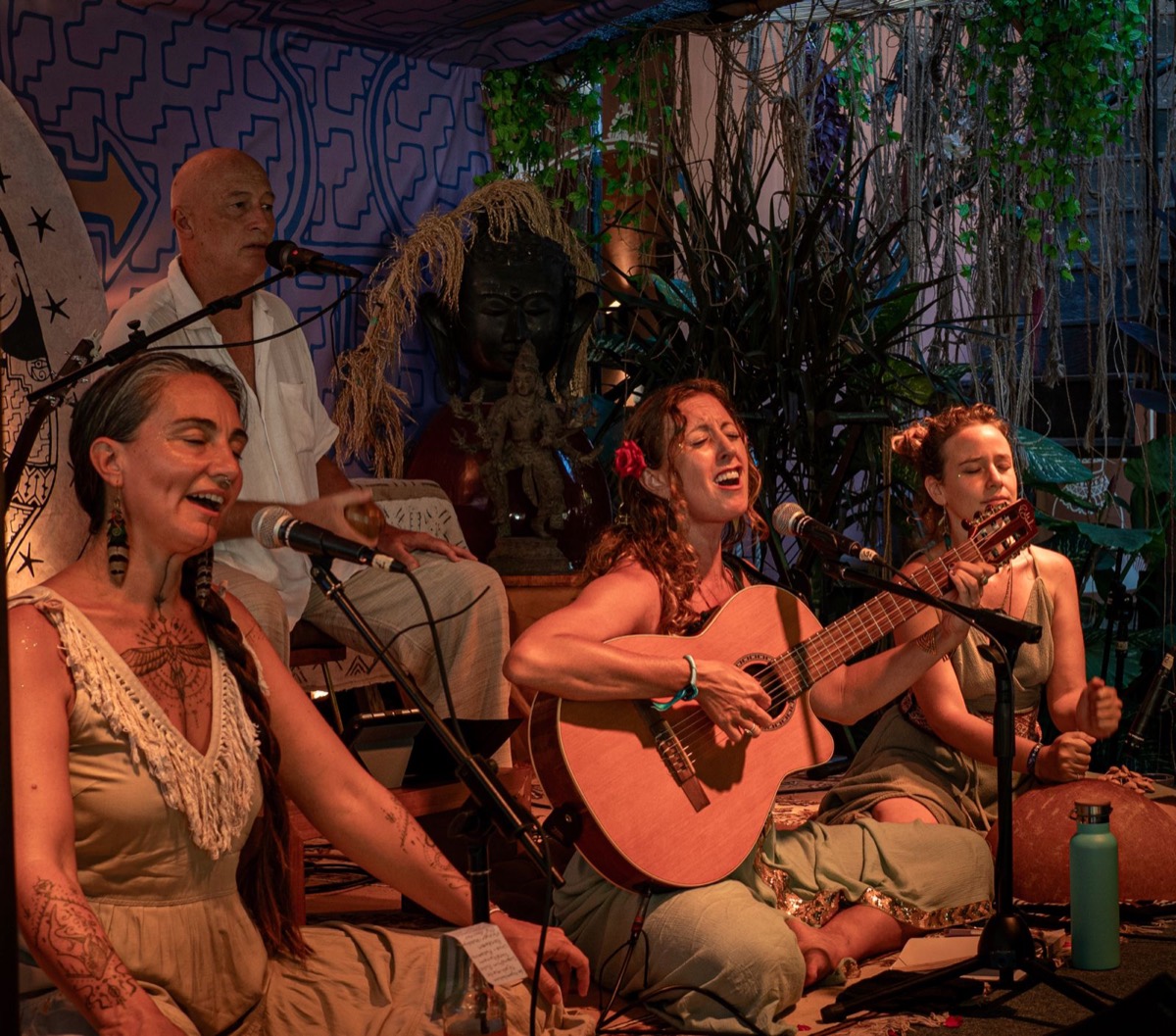 Francie La Flow singing and playing guitar mid-song with her band in Bali, a red rose in her hair