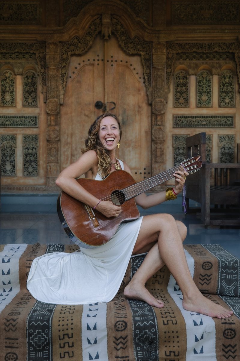 Francie with her guitar in front of carved Balinese doors